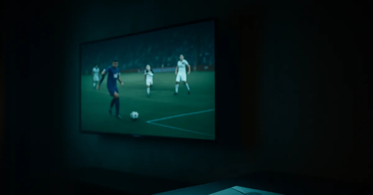 Nowoczesny Smart TV wiszący na ciemnej ścianie wieczorem, wyświetlający mecz piłkarski, bez podłączonej anteny, obok urzędowa koperta w chłodnym świetle.